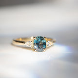 Daintree | 'Four Seasons' | Madagascan Teal Sapphire & Pear Diamonds Trilogy Ring made with 18K yellow gold in bright sunlight
