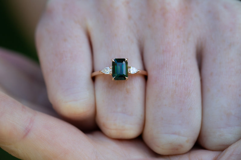 Close up of Forest Green Teal Sapphire & Pear Diamonds Ring on finger
