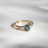Daintree | 'Four Seasons' | Madagascan Teal Sapphire & Pear Diamonds Trilogy Ring made with 18K yellow gold in sunlight and with a tilted view