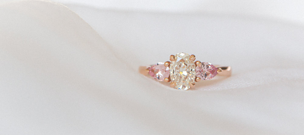 Rose gold ring with a diamond and lotus sapphires on a white background