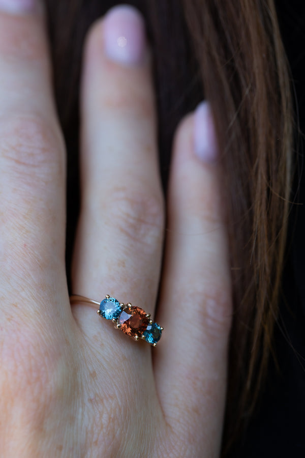 Orange & Blue-Green Teal Sapphires Ring on engagement ring finger