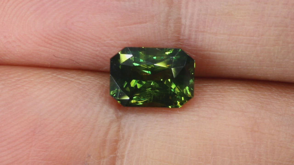 Video of 2.05Ct Forest Green Teal Sapphire | Emerald Shape from Madagascar between fingers
